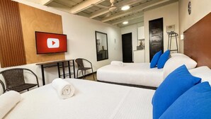 Ein Hotelzimmer mit zwei Betten, einem Fernseher, einem Schreibtisch und einem Stuhl.