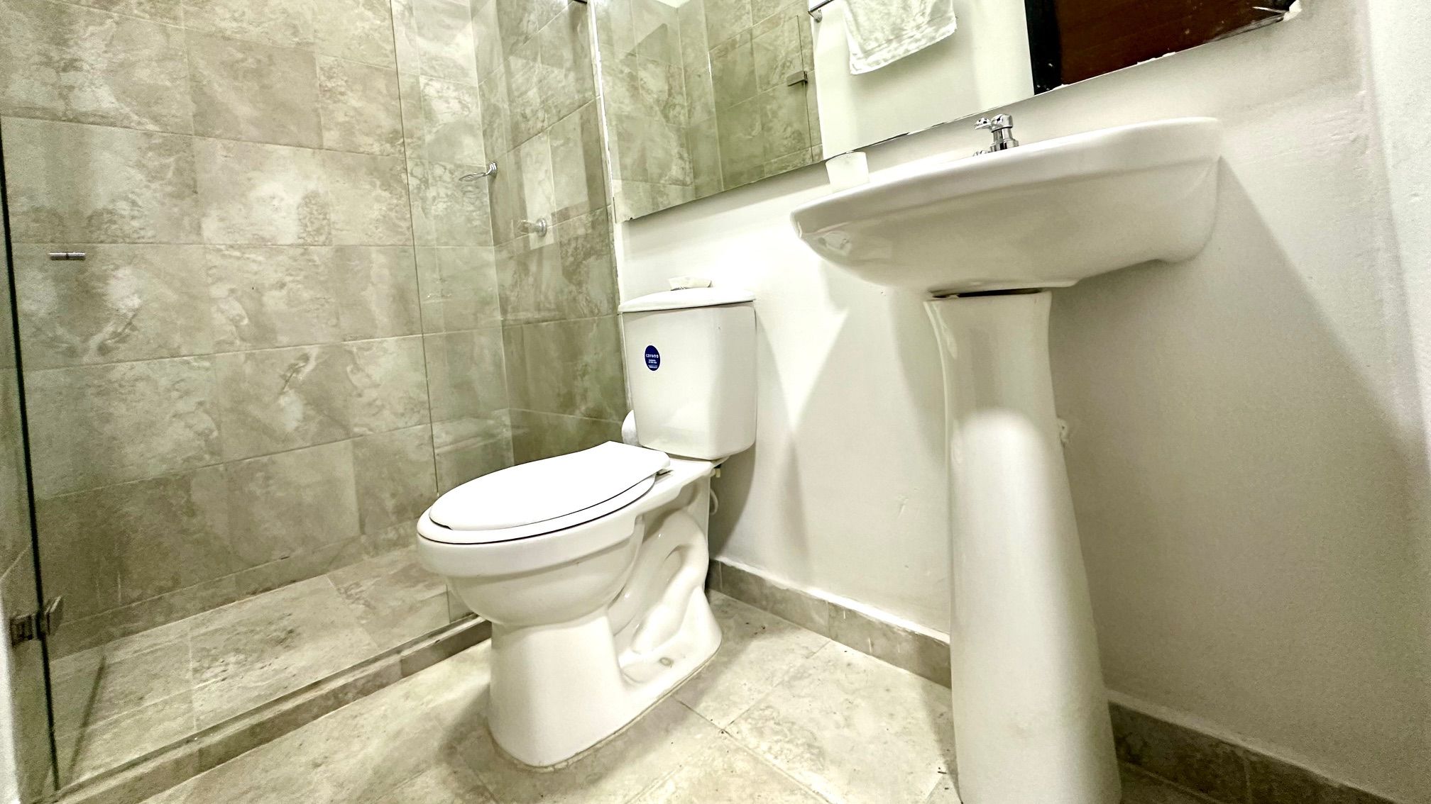 Un baño con inodoro, lavamanos y zona de ducha.
