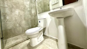 Un baño con inodoro, lavamanos y zona de ducha.