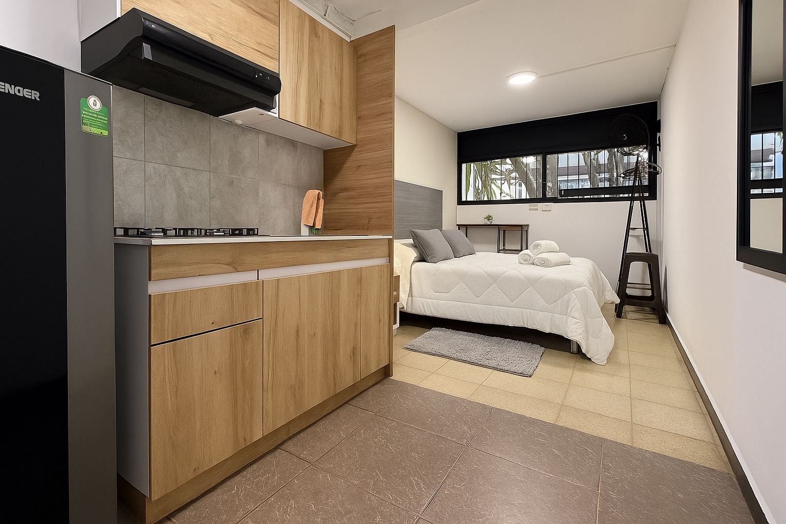 Un dormitorio pequeño con cama, mesita de noche y ventana.