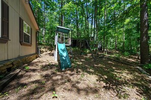 Une cabane dotée d’un porche, entourée d’une zone boisée.
