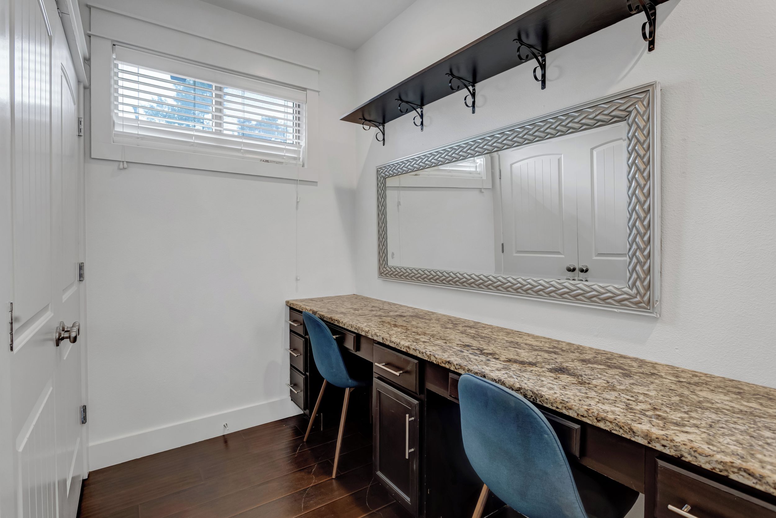 A kitchen with a granite countertop, two dark cabinets, a double door, and a window with blinds.