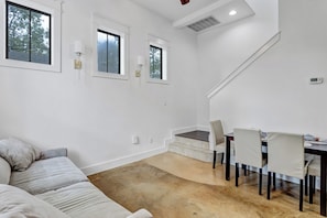 Ein modernes Wohnzimmer mit einer Couch, einem Esstisch mit Stühlen und einer Treppe.