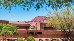 A building with a sign reading 'Sand Point at Entrada' and a mountain in the background.
