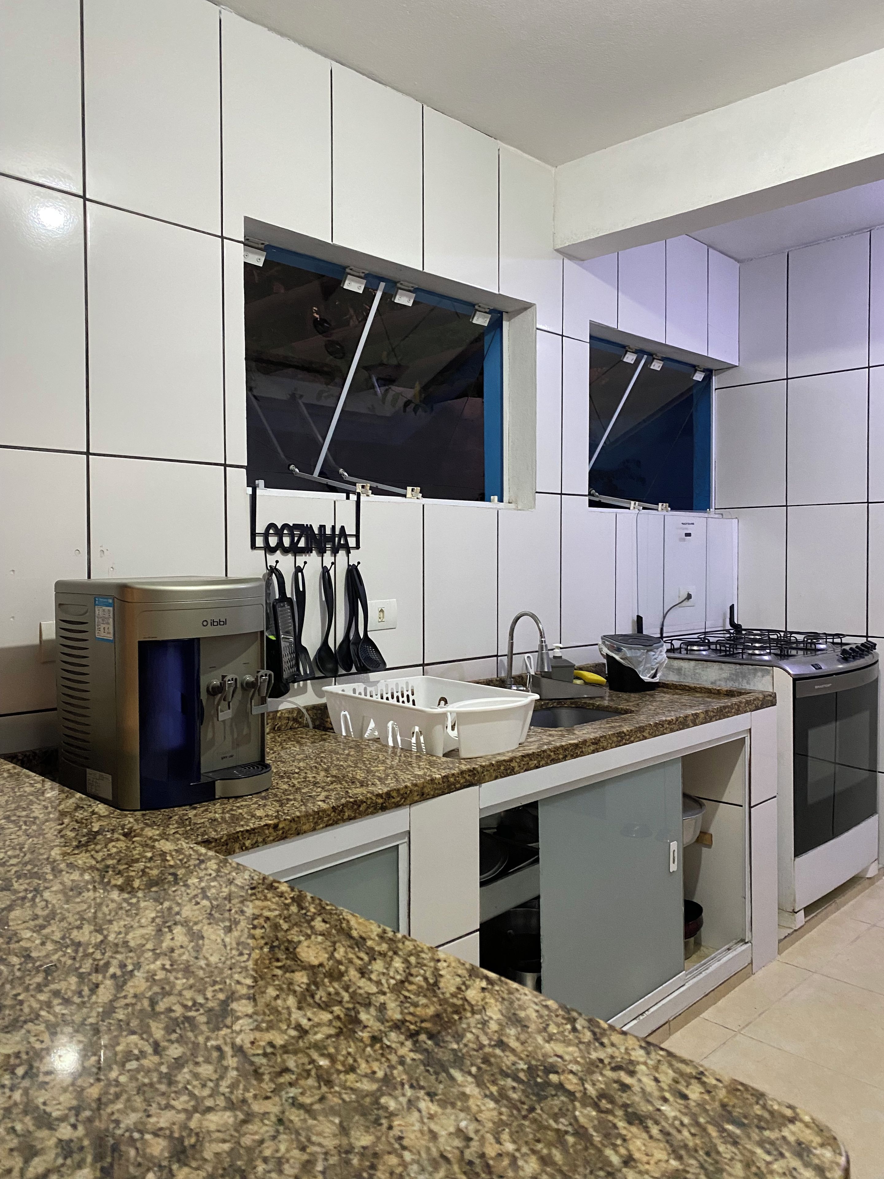 Una cocina moderna con armarios blancos, encimera de granito, horno empotrado y cafetera.