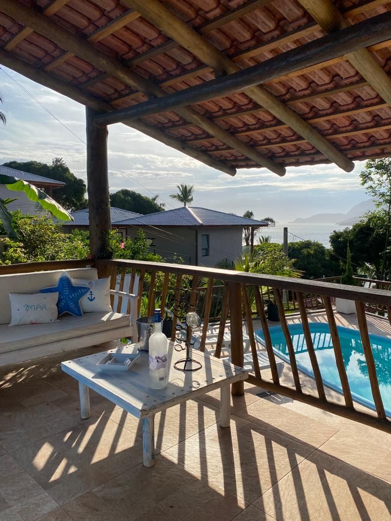 A covered outdoor area with a pool, a wooden deck, and a seating area with a starfish pillow.