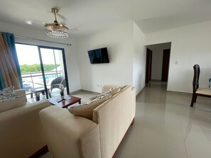 A modern living room with a sofa, a coffee table, and a television mounted on the wall. - APARTAMENTO COMPLETO A 2 MINUTOS DE LA PLAYA CON PISCINA 3 DORMITORIOS 2 BAÑOS (La Romana)