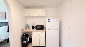 A compact kitchenette with a microwave, refrigerator, and a small countertop with a blender and other items. - Cozy Beach Studio | Sleeps 4 | First floor (Myrtle Beach)