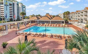 Une piscine d’hôtel avec des chaises longues et un bâtiment en arrière-plan.