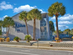 A building with a sign reading 'John's Inn' and a modern architectural design with a balcony. - Sunny Beach Retreat | 2 Queens (Myrtle Beach)