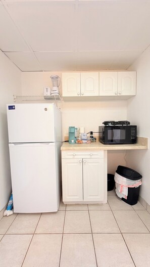 A compact kitchen with a refrigerator, microwave, and a coffee maker on the countertop. - Sunny Beach Retreat | 2 Queens (Myrtle Beach)
