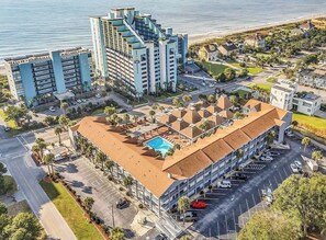 Um hotel com piscina no terraço, estacionamento próximo e vista para a praia.
