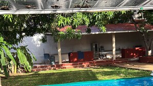 A swimming pool with a covered area and a building in the background.