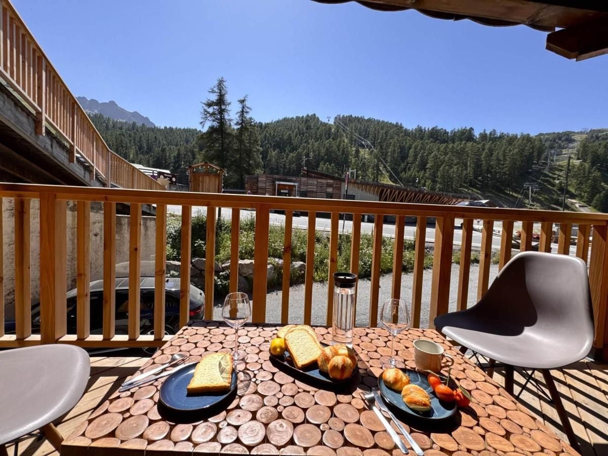 Una terraza de madera con una mesa dispuesta para una comida, con vista a un paisaje montañoso.