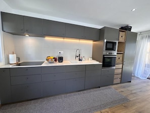 A modern kitchen with grey cabinetry, a built-in oven, and a microwave. - 100m from ski slopes, view mountain, terrace, tv, 82m², Vars (Vars)
