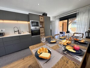 A modern kitchen with built-in appliances and a dining area set for a meal. - 100m from ski slopes, view mountain, terrace, tv, 82m², Vars (Vars)