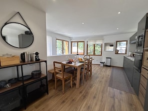 A modern kitchen with a dining area, wooden flooring, and large windows. - 100m from ski slopes, view mountain, terrace, tv, 82m², Vars (Vars)