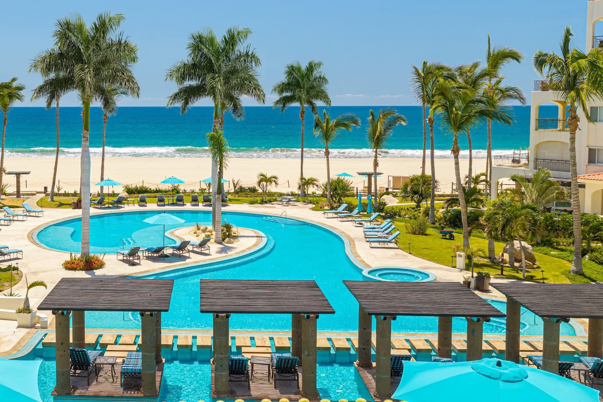 Ein Resort mit großem Pool, Liegestühlen und Palmen.