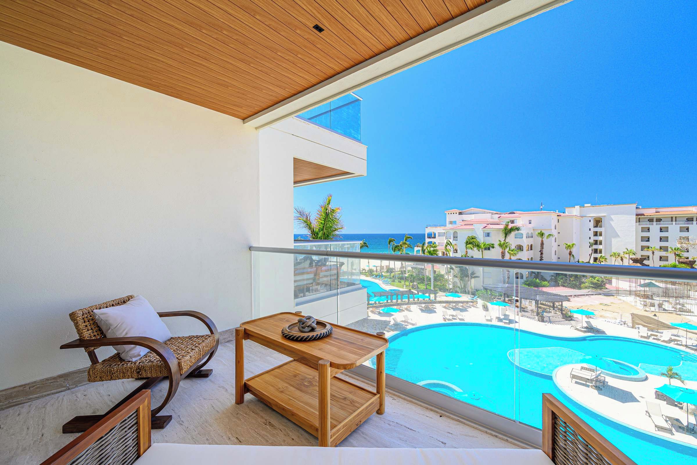 Un balcon avec vue sur une piscine et les bâtiments d’un complexe hôtelier.