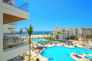 A resort with a large pool area, palm trees, and a view of the ocean. - Beachfront 3BR Condo at Tortuga Bay by The Agency Baja Travel (San José del Cabo)