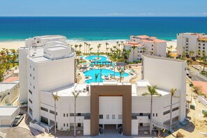 Un complejo turístico con piscina central, varios balcones y vistas a la playa.