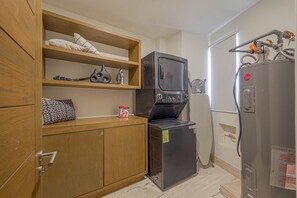 A compact kitchen with wooden cabinets, a built-in microwave, and a refrigerator. - Beachfront 3BR Condo at Tortuga Bay by The Agency Baja Travel (San José del Cabo)