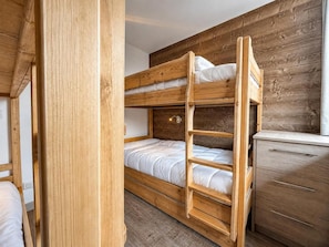 Ein Schlafzimmer mit Etagenbett, einem hölzernen Kopfteil, einem Schminktisch und einem Fenster.