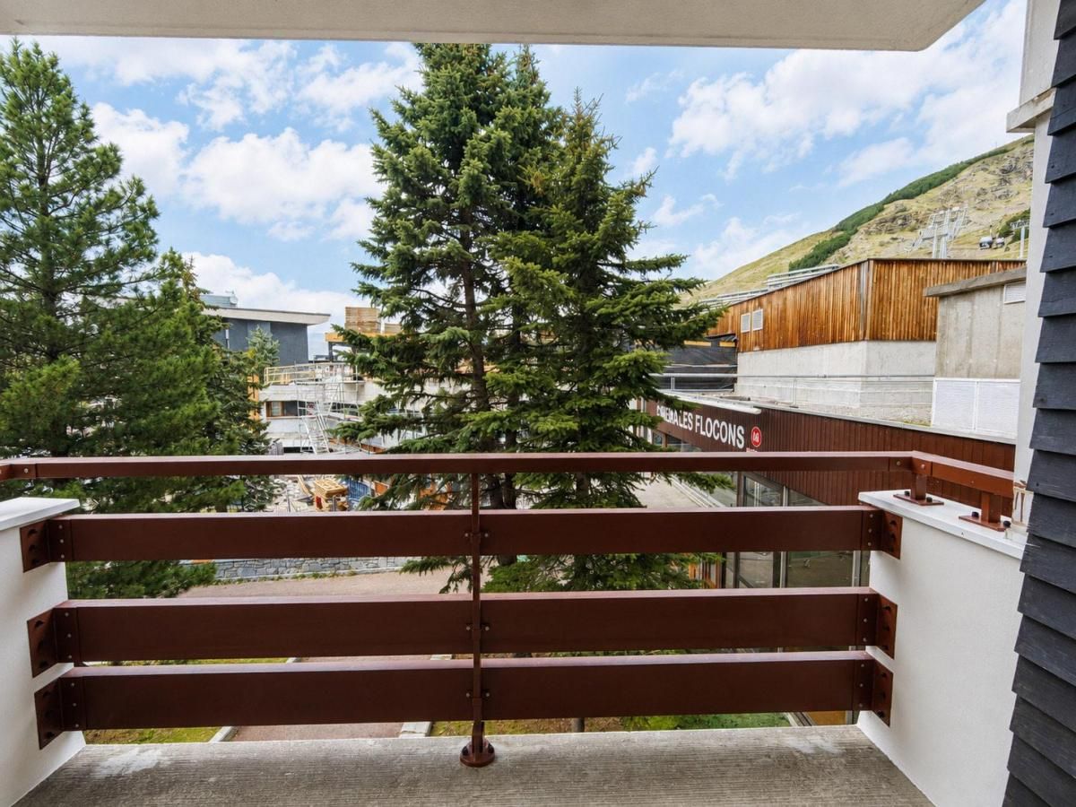 A balcony with a metal railing, overlooking a construction site and a building with a sign that reads 'FENALLES FLOONS.'