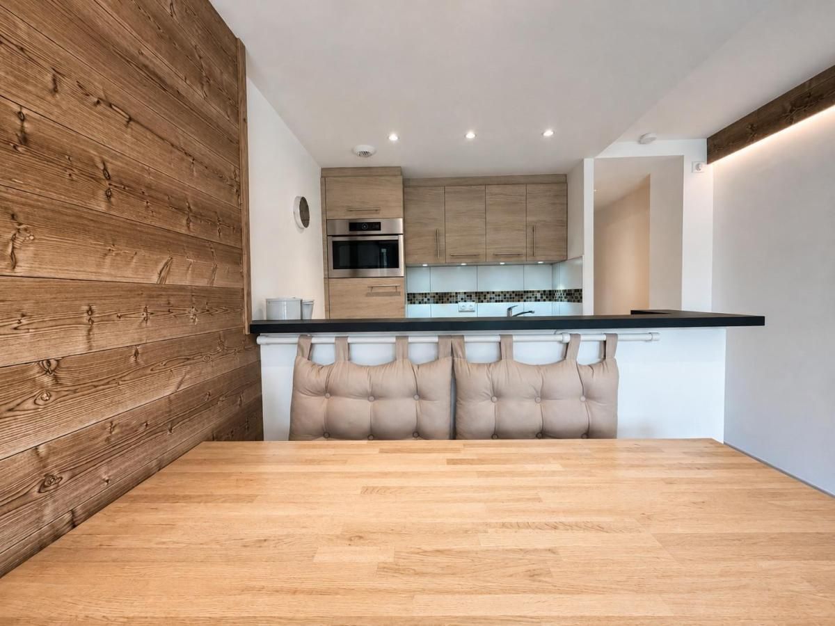 Una cocina moderna con armarios de madera, horno de acero inoxidable y encimera negra.