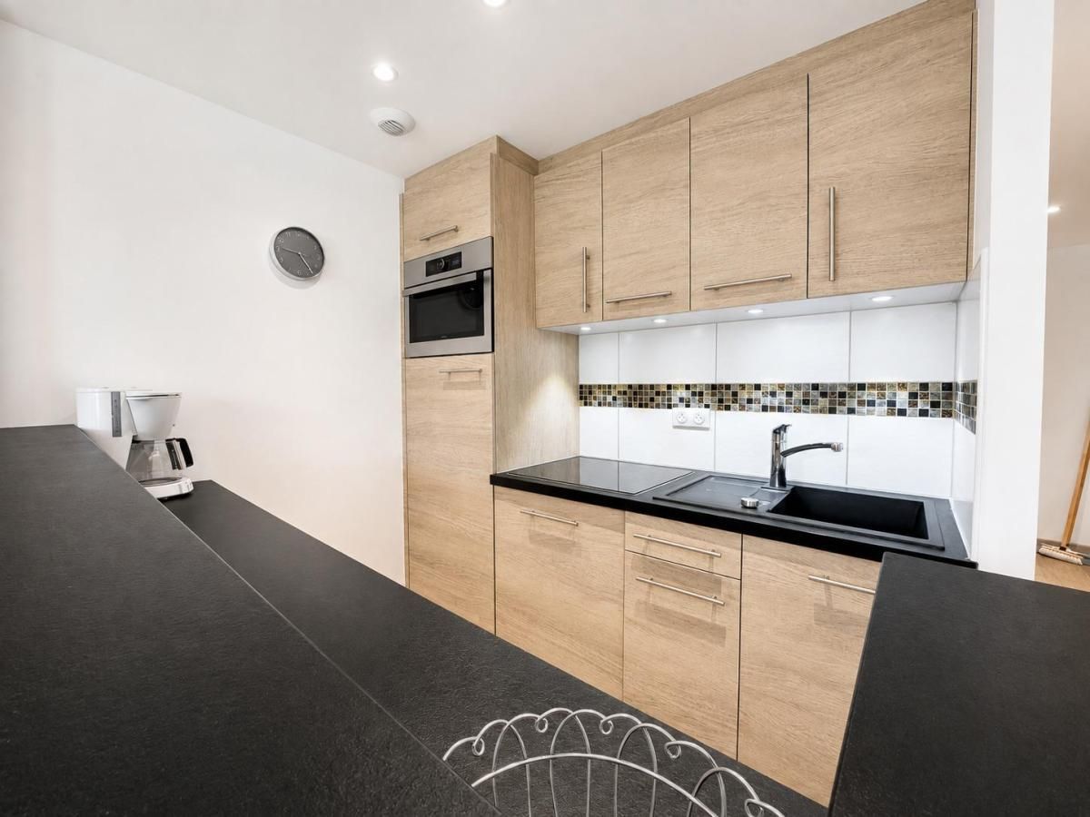 Eine moderne Küche mit Holzausstattung, einer schwarzen Arbeitsplatte und einem eingebauten Backofen.