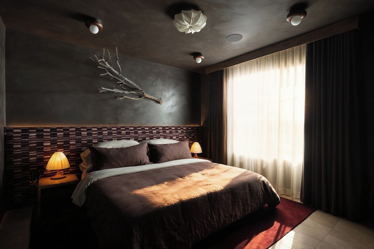 A modern hotel room with a large bed, a decorative wall piece, and a view of the outdoors.