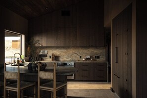 Eine moderne Küche mit Kochinsel, Holzschränken und einer Steinrückwand.