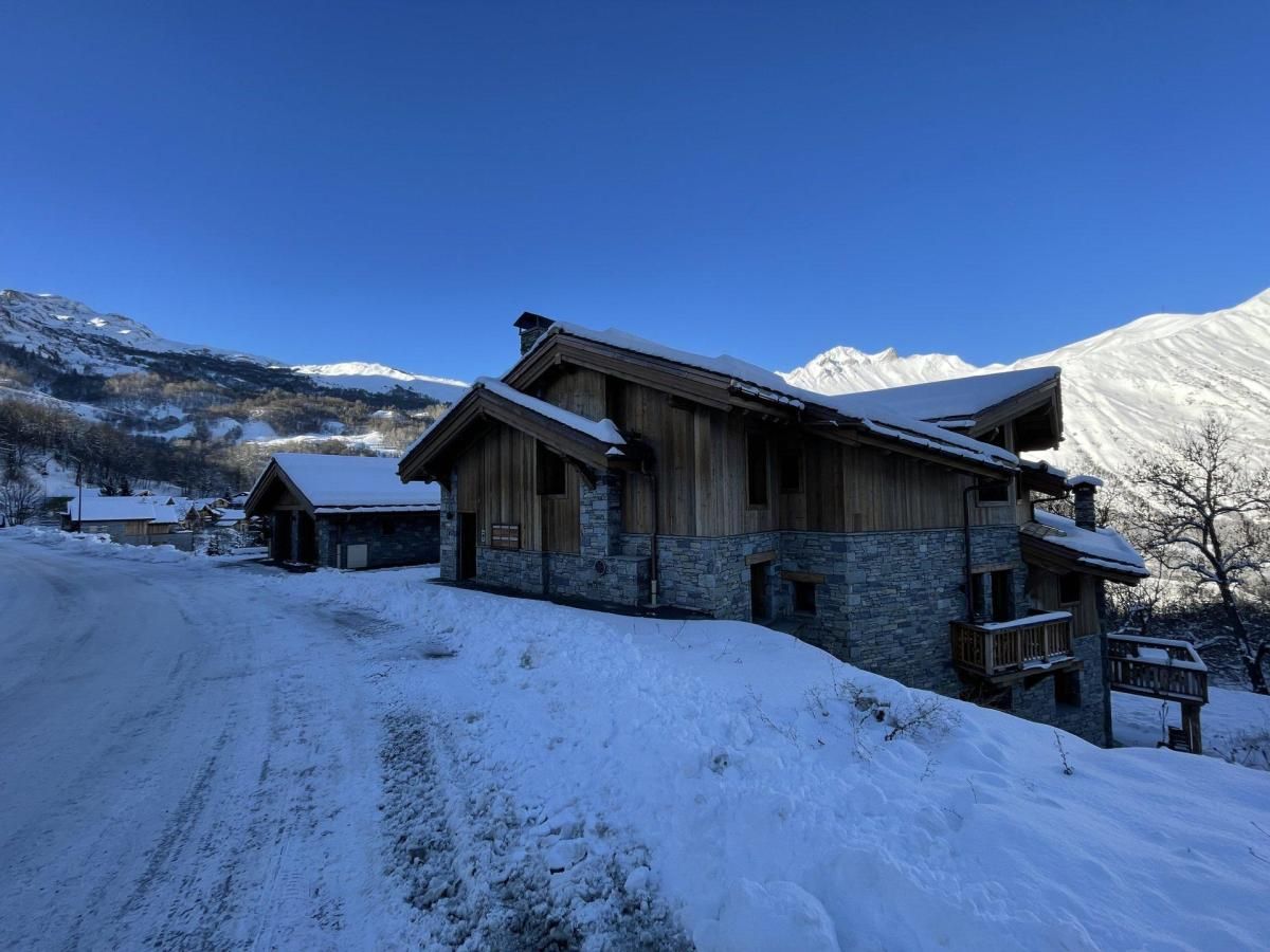 Een houten lodge met stenen muren, een balkon en een besneeerd landschap op de achtergrond.