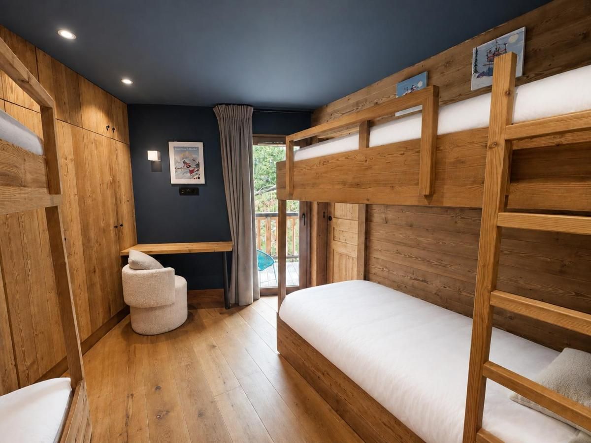 Une chambre avec des lits superposés, un petit coin salon et une fenêtre avec des rideaux.