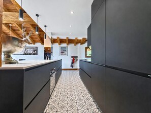 Eine moderne Küche mit dunklen Schränken, einem gemusterten Boden und Holzbalken an der Decke.