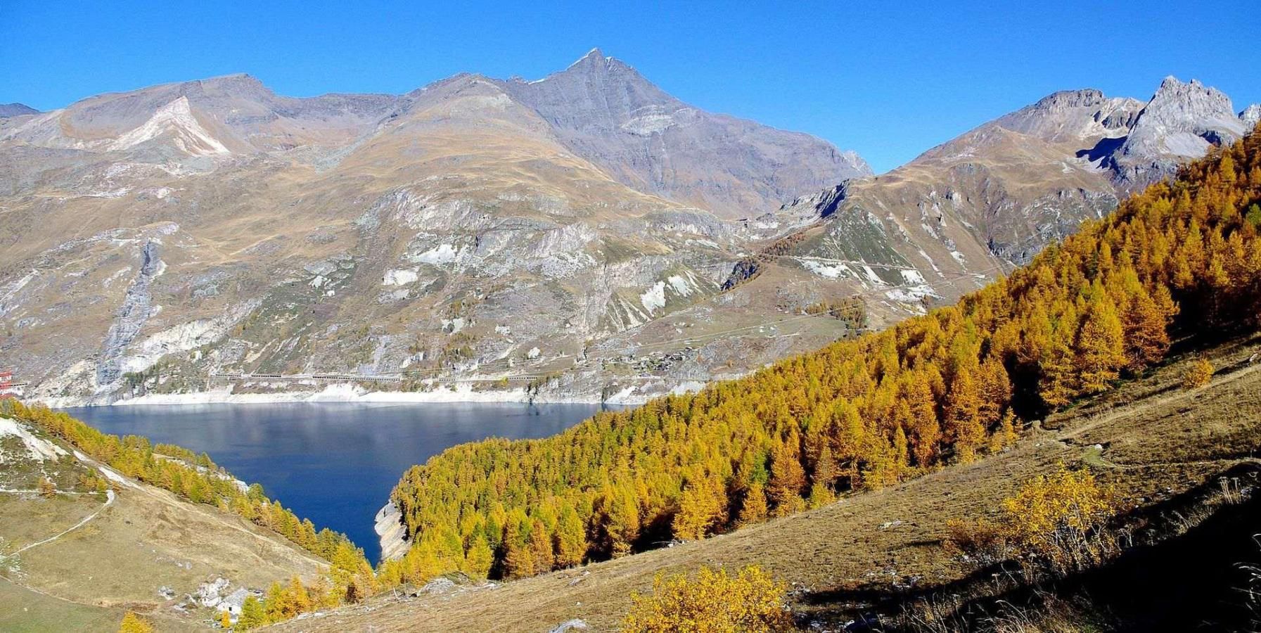 A mountainous landscape with a lake, forested area, and a clear sky.