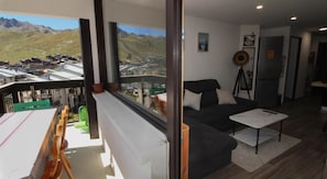 A modern living room with a sofa, a small table, and a view of a mountainous landscape through large windows. - 150m from ski lifts, 7th floor, balcony, tv, ski locker, 35m², Tignes (Tignes)