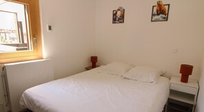 A bedroom with a bed, two bedside tables, a window, and two wall-mounted pictures. - 150m from ski lifts, 7th floor, balcony, tv, ski locker, 35m², Tignes (Tignes)