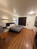 Una habitación de hotel con una cama, un escritorio, una silla, una puerta y una mesita.