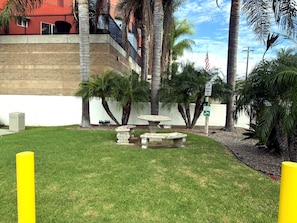 A courtyard with a fountain, palm trees, and a building with a red facade. - Odyssey Inn (National City)