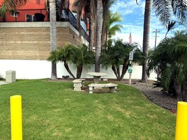 Un patio con una fuente, palmeras y un edificio de fachada roja.