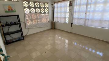 A room with a tiled floor, a ceiling fan, and windows with curtains.