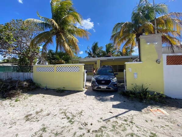 A gated property with a parked vehicle, palm trees, and a clear sky.