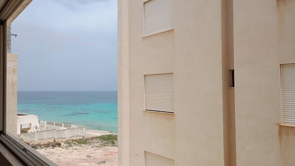 A view from a window overlooking a beach with a building in the foreground.