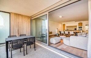 Uma sala de estar moderna com sofá, pufes e um espaço de jantar com cadeiras e mesa.