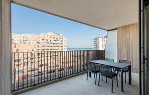 A balcony with a table and chairs, overlooking a beach and buildings. - 3 bedroom luxurious apartment in Oostende (Oostende)