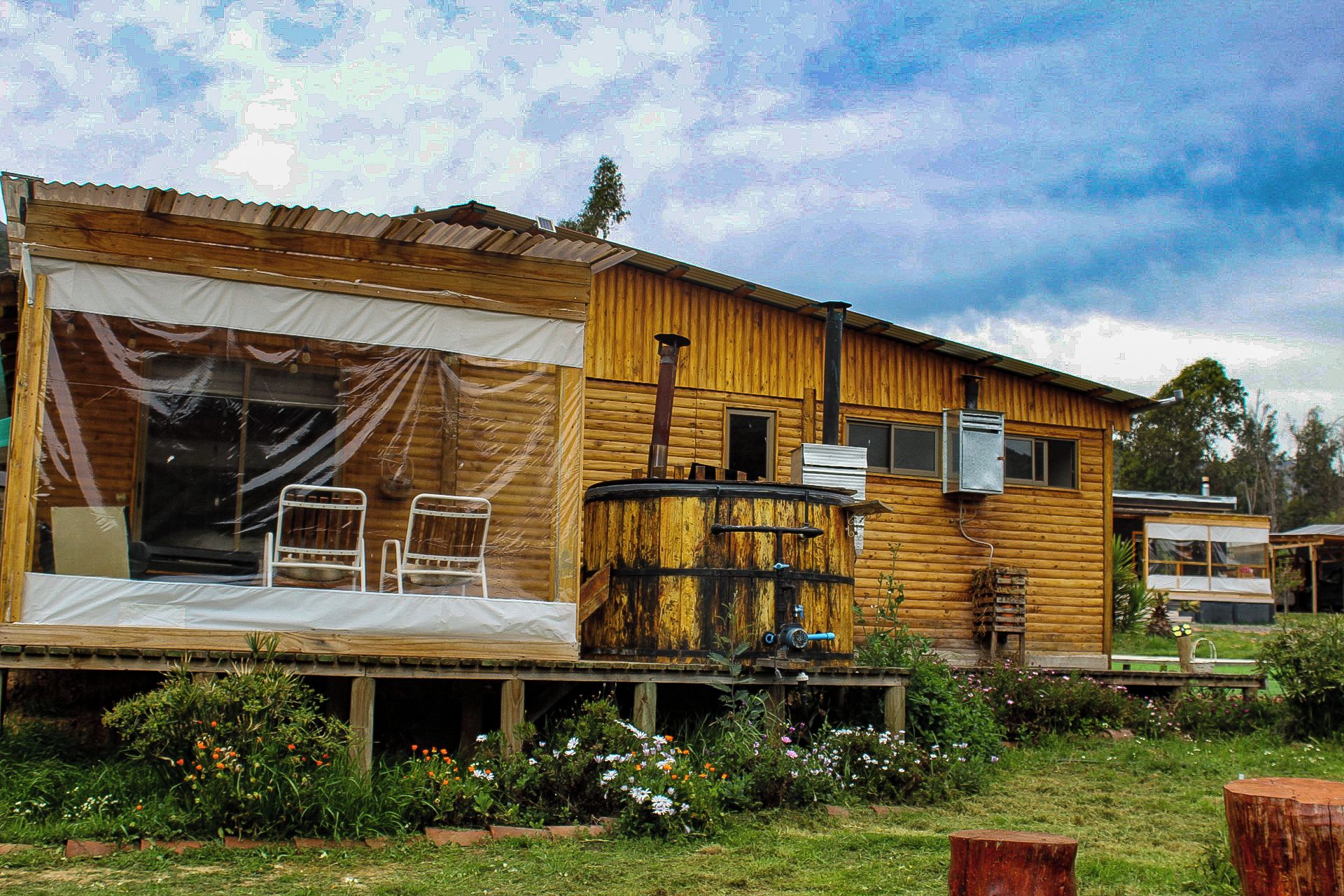 A rustic wooden cabin with a covered porch, a large window, and a visible chimney.