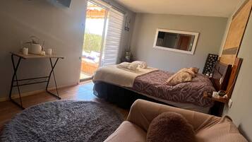 A bedroom with a bed, a sofa, a small table, and a window.