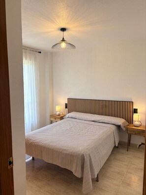 A bedroom with a bed, bedside lamps, a hanging light fixture, and a window with curtains. - Sun & Beach in the Heart of Torrevieja (Torrevieja)
