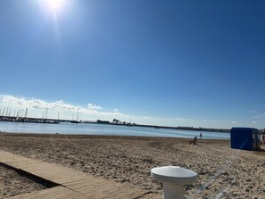 A beach with a wooden walkway, a white structure, and a blue kiosk. - Sun & Beach in the Heart of Torrevieja (Torrevieja)